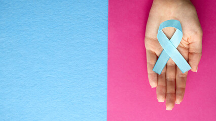 Blue ribbon in support of trafficking and sexual slavery. Blue ribbon on female hands on a blue...