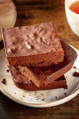Chocolate brownie with tea close-up, simple coffee cake, on a dark rustic wooden background, gourmet breakfast