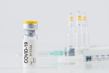 Coronavirus vaccine vial glass with a syringe on white background.