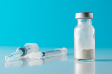 Vaccine vial glass with a syringe on blue background. Medicine vaccination concept. World pandemic concept.