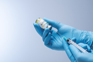 Doctor in blue latex gloves fill in syringe with vaccine from glass vial. Vaccination,...