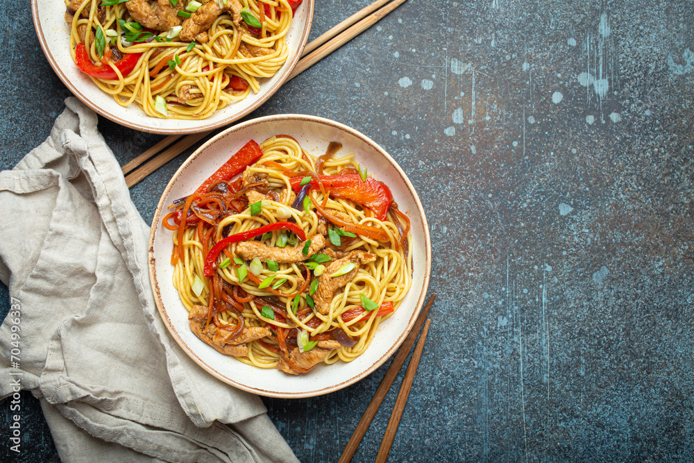 Poster two bowls with chow mein or lo mein, traditional chinese stir fry noodles with meat and vegetables, 