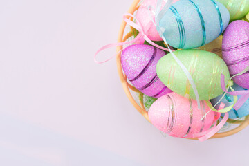 Easter party background with multi colored different eggs in pink, green, blue colors lying in nest basket.Copy space backdrop