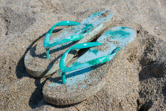 Blue colored summer shoe sandals on sandy bech at bright sunlight.Holiday vacation and tourism concept