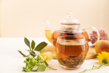 Red tea with herbs in glass teapot on white wooden. Top view, selective focus.
