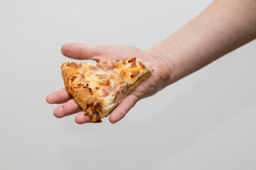 A Caucasian man holds a slice of pizza in a hand.