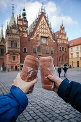 female and male hands holding trdelnik against the background of an ancient building in the center of Wroclaw