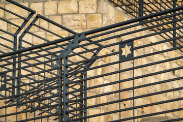 Focused view of a Star of David prominently displayed on a metal barrier, symbolizing Jewish identity against a backdrop of aged stone