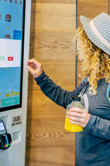 Woman make food order in modern display at fast food restaurant - self-service panel technology and...