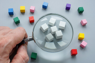 Ethnocentrism concept. White cubes and magnifying glass.