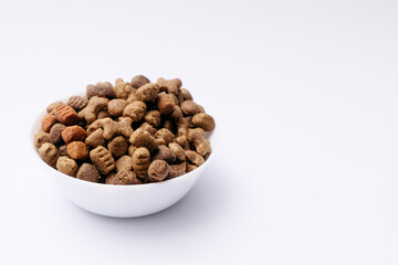 Dry dog food in a white bowl close-up on a white background. Pet diet concept.