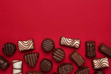 Beautiful chocolate sweets on a red background. Happy Valentine's Day greeting cards. Place for your decorations or text, top view, flat lay.