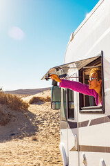 Adult tourist woman opening camper van window to enjoy the sun and freedom. Concept of travel people for summer holiday vacation inside camping car motorhome vehicle. Freedom nomad lifestyle - obrazy, fototapety, plakaty