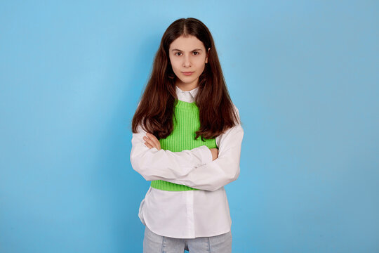 Young brunette teenage girl angry and offended on blue background.