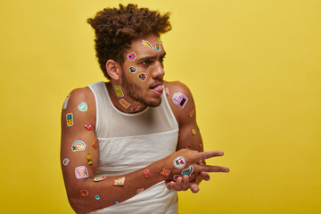 funny african american guy in tank top with stickers on face sticking out tongue on green backdrop - obrazy, fototapety, plakaty