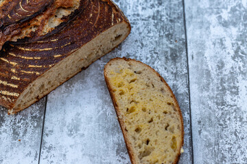 A loaf of sourdough bread, with a slice with melting butter seeping through the holes