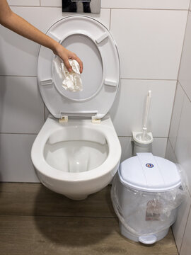 Hand throw toilet paper into the toilet bowl