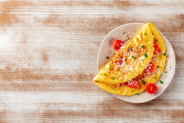 An omelet with tomato and parsley, eggs for breakfast, a healthy vegetarian dish with cheese, shot from above with a place for text - obrazy, fototapety, plakaty