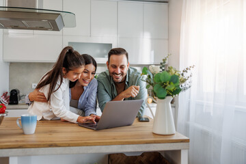 Happy family with daughter having fun in their kitchen, using laptop