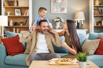 Mom, dad and son are eating pizza at home