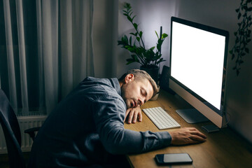 A tired entrepreneur is sitting at his home office and sleeping late at night.