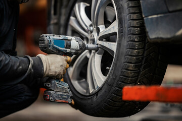 Fototapeta na wymiar Cropped picture of a a mechanic's hands installing car wheel in vulcanizing workshop.