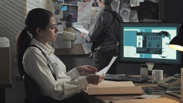 female detective in office searching evidence,woman police officer working on the murder case examining killer identikit