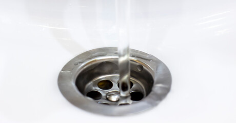 A close up photo captures a water drain in a sleek sink, with clear water flowing effortlessly from...