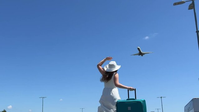 View from the back of a little baby girl waving through an airport terminal window to a taking off jet. Daughter saying goodbye to the departing plane. High quality 4k footage. High quality 4k footage