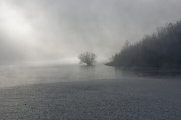 Panoramic view of Lake Turano. Lake in the mystical fog. Winter landscape with town on the rock....