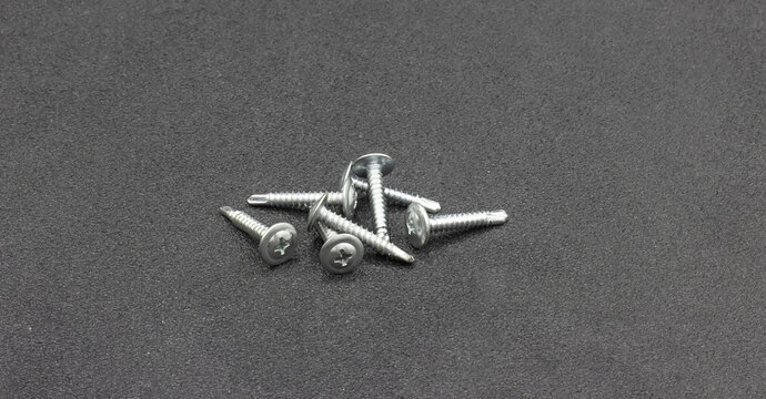 Self tapping screws with a press washer for metal with a drill, showcased on a black matte background.