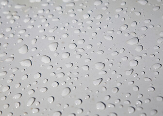 Detalhe de gotas de agua da chuva em cima de chapa pintada de branco. 