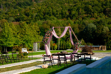 Wedding arch decoration. Elegant ceremony in Bulgarian beautiful nature. Flower arch pink cloth and...