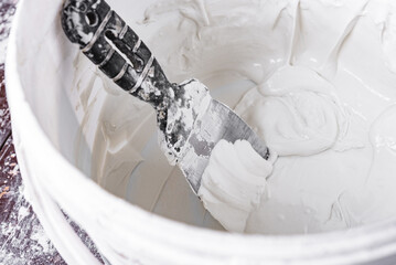 Spatula with putty on bathroom background.