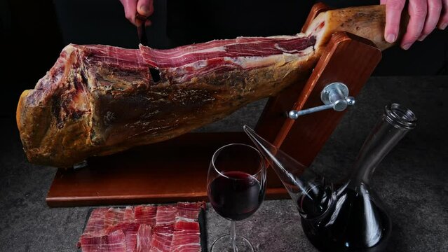 Man cutting slicing a traditional Iberico Spanish ham, jamon. Whole leg. 