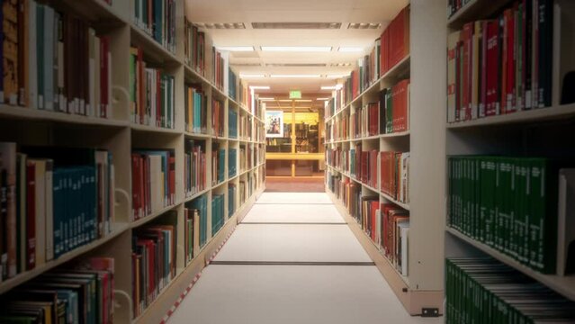 Bookshelves Corridor Zooming Through Books Hallway Tracking Shot. Camera zooming through a library corridor between bookshelves. Tracking shot