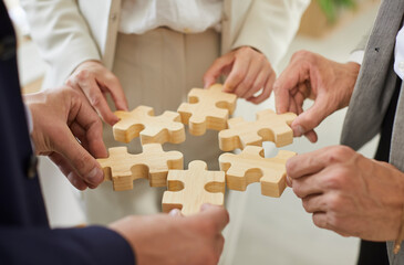 Business team trying to solve a problem together. Group of people holding pieces of a jigsaw...