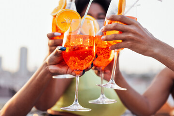 Close up of female and male hands holding elegant glasses with long stem of aperol and clink them.