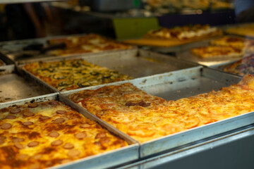 Authentic Italian pizza in a restaurant display window. Various pizzeria in glass window display. Focus on pizza with tomatoes