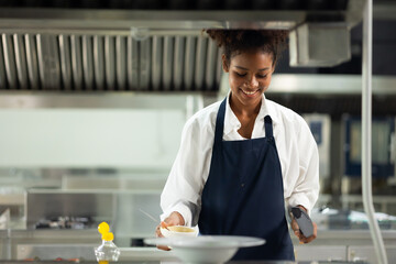Happy African American woman standing with arms crossed while working as chef in a restaurant. Cooking class. culinary classroom. happy young african woman students cooking in cooking school. - obrazy, fototapety, plakaty