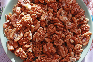 Shelled walnut kernel in plate on kitchen table.