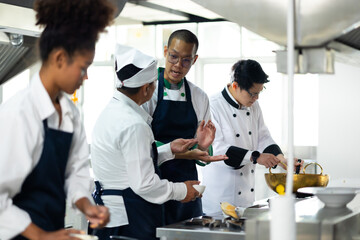 Group of student learning. Cooking class. culinary classroom. group of happy mature man and young woman multi - ethnic students are focusing on cooking lessons in a cooking school. - obrazy, fototapety, plakaty