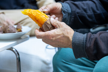Old man eating sweet potato