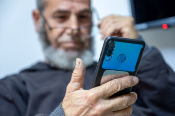 old man holding phone while focusing due to poor eye vision