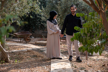 A husband walks with his pregnant wife in the park, exchanging loving glances and feeling excited about the approaching time of birth