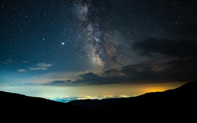 Milky way's core seen seen from the mountains, rising above urban city pollution in a summer night....