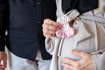 Pregnant female holding small wool knitted clothes