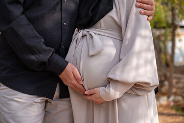 male touching his wife belly in garden and feeling excited for his new baby