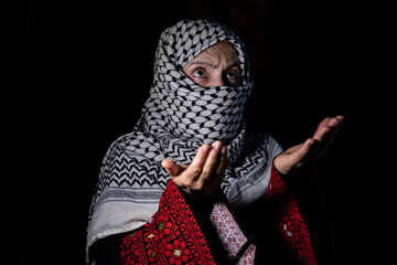 portrait for person praying to allah with white keffiyeh on his face in dark background