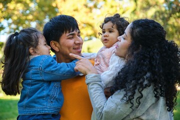 Latin happy family with two children together in a park.
